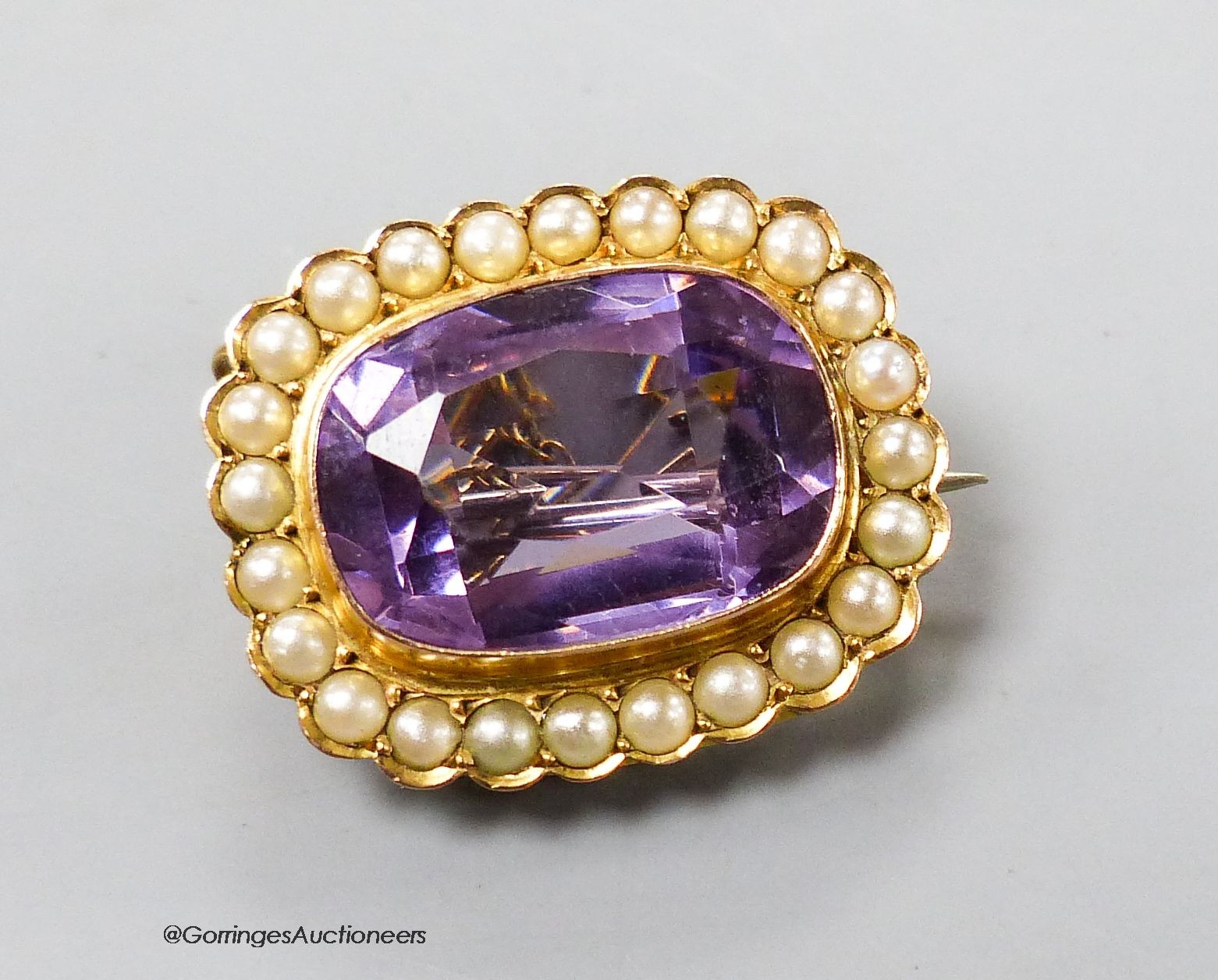 An Edwardian 9ct gold, amethyst and split pearl set oval brooch, 25mm, gross 6.6 grams.